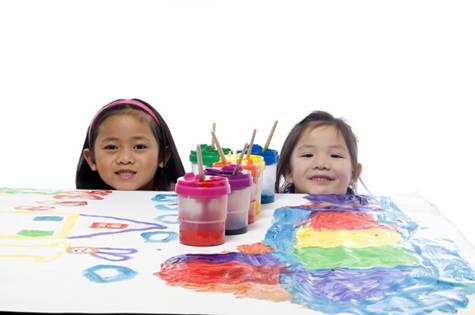 2 smiling girls in front of a painting