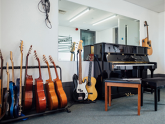 a music room with guitars, a piano and a piano bench