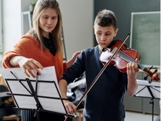 teacher is teaching a child how to play violin