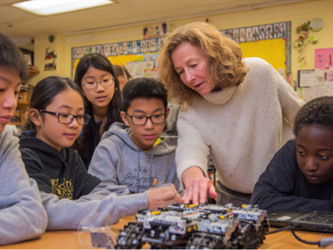 a group of students working on a robot in a classroom