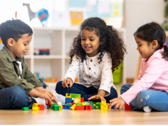 three children playing with blocks on the floor