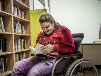 girl on a wheelchair reading in the library